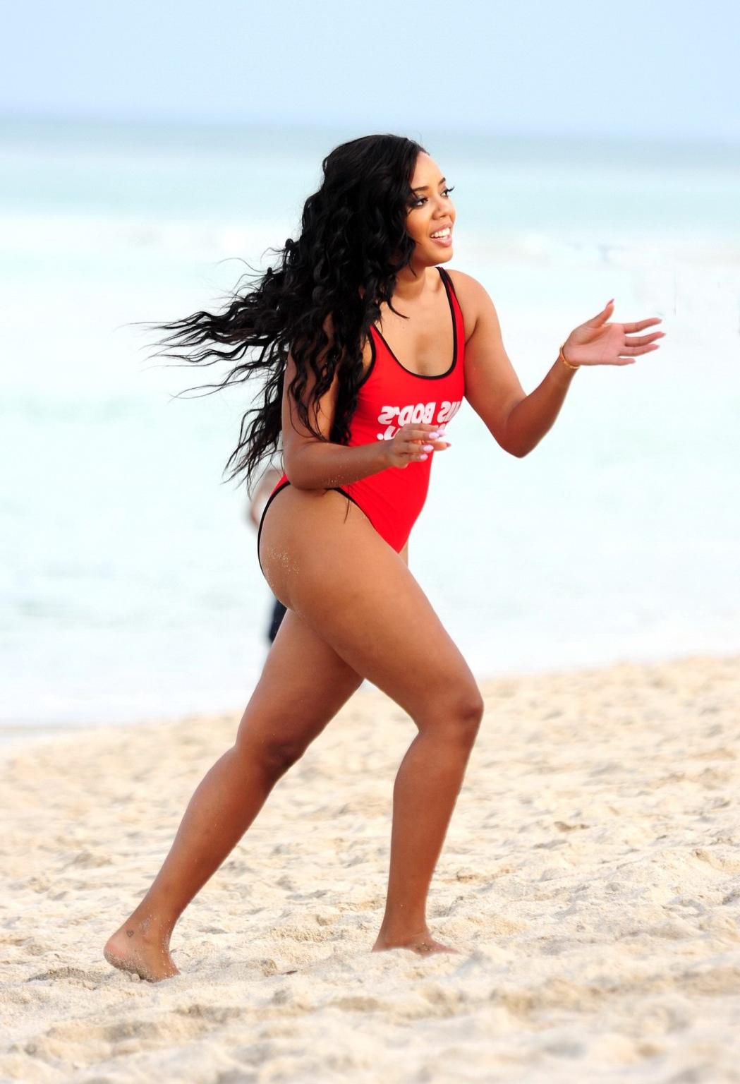 12P Angela Simmons in red swimsuit doing a bridge on a beach in Miami