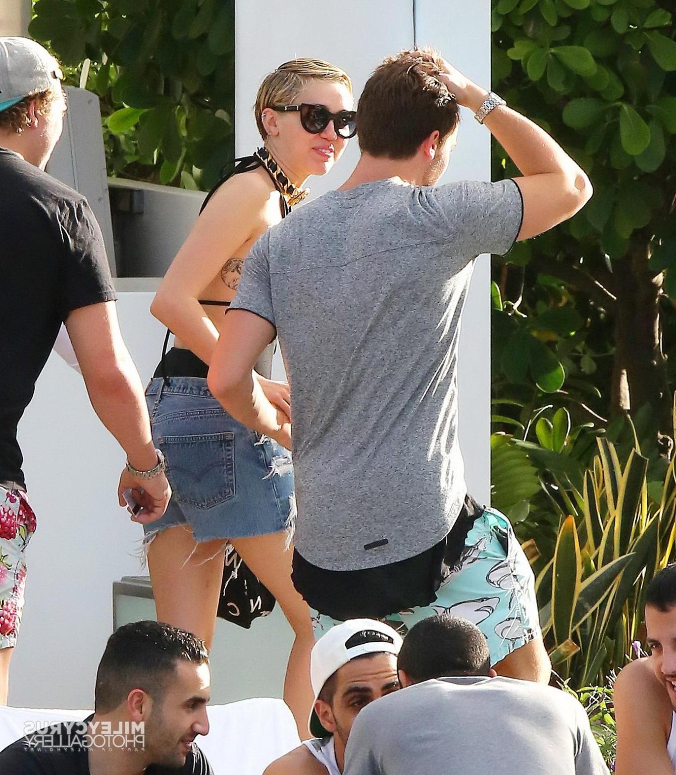 16P Miley Cyrus wearing swimsuit and hotpants at a pool in Miami