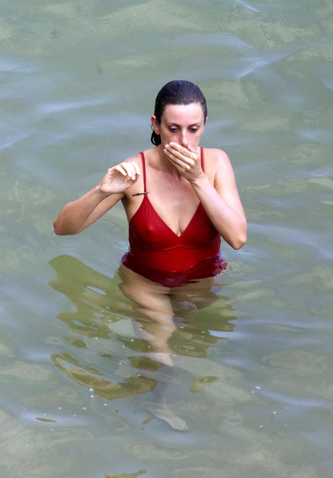 16P Penelope Cruz showing pokies on a beach wearing a sexy red swimsuit