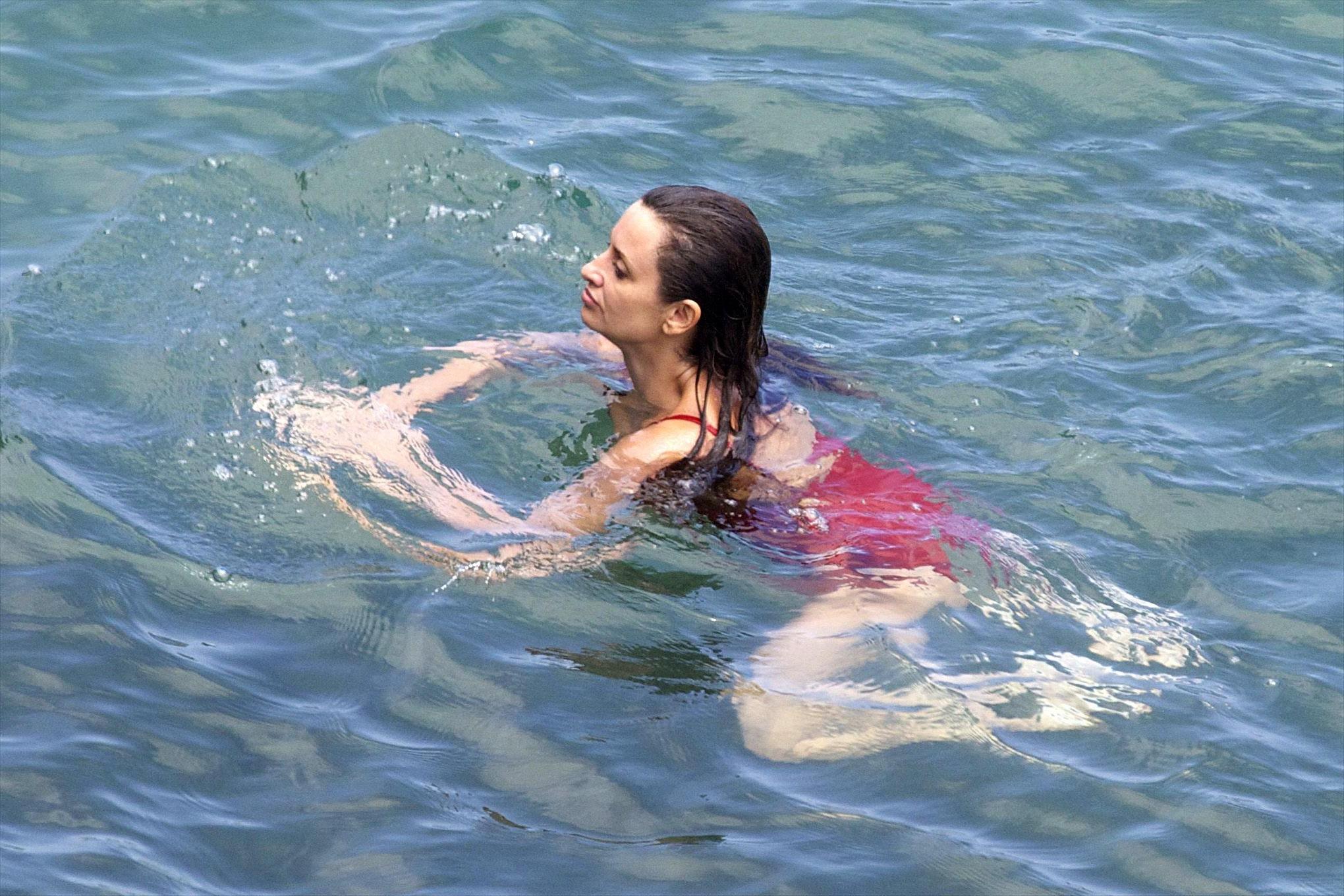16P Penelope Cruz showing pokies on a beach wearing a sexy red swimsuit