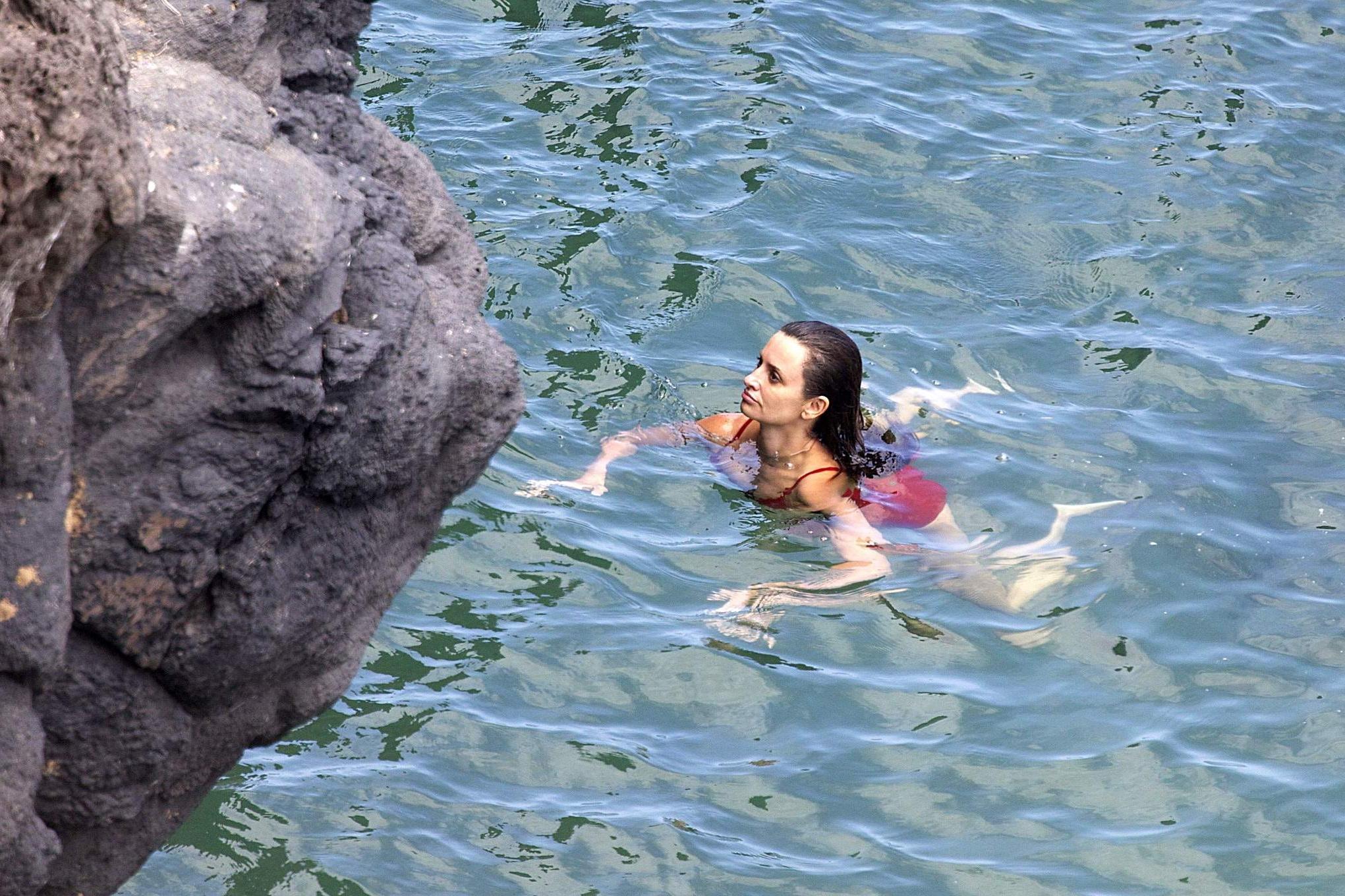 16P Penelope Cruz showing pokies on a beach wearing a sexy red swimsuit