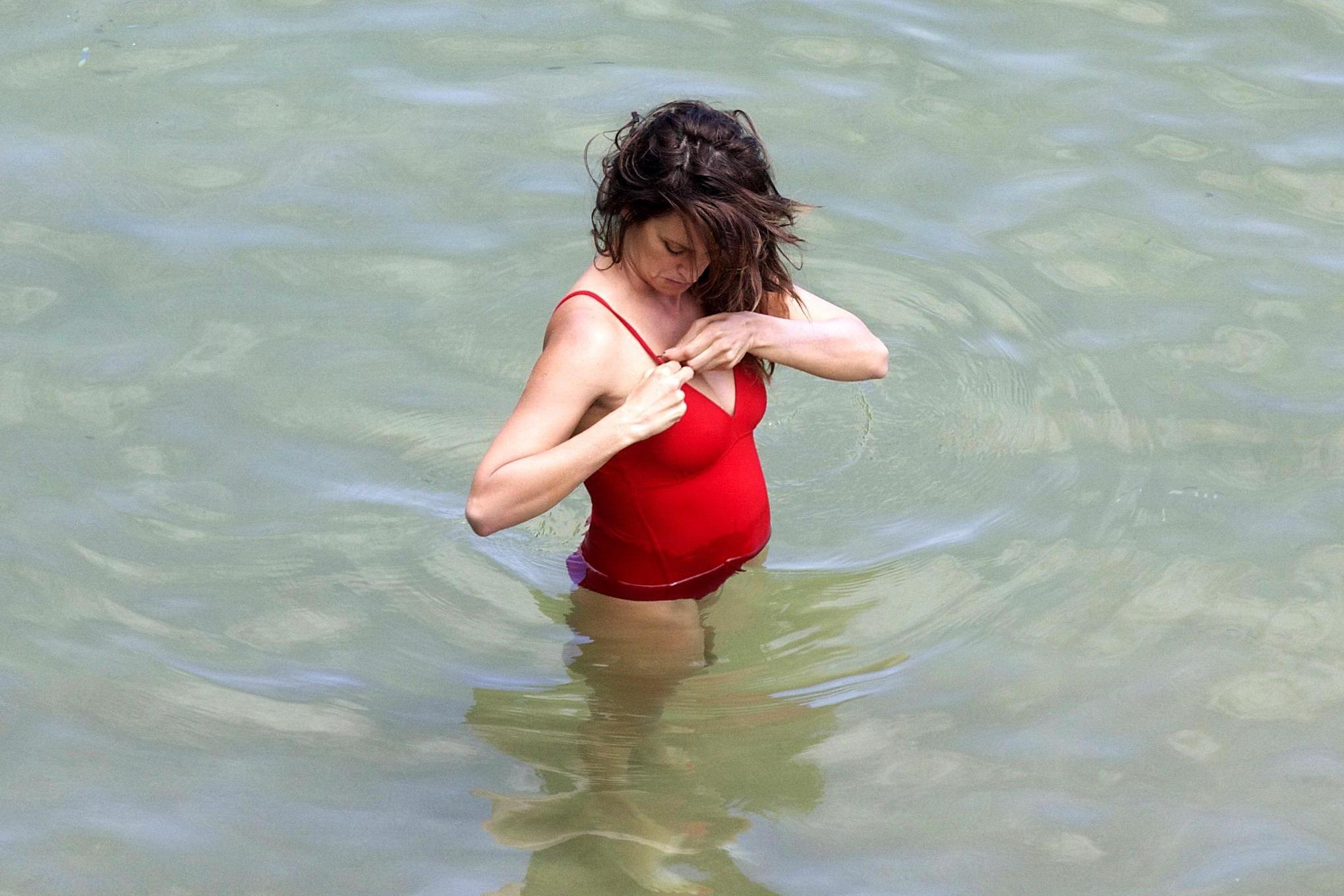 16P Penelope Cruz showing pokies on a beach wearing a sexy red swimsuit