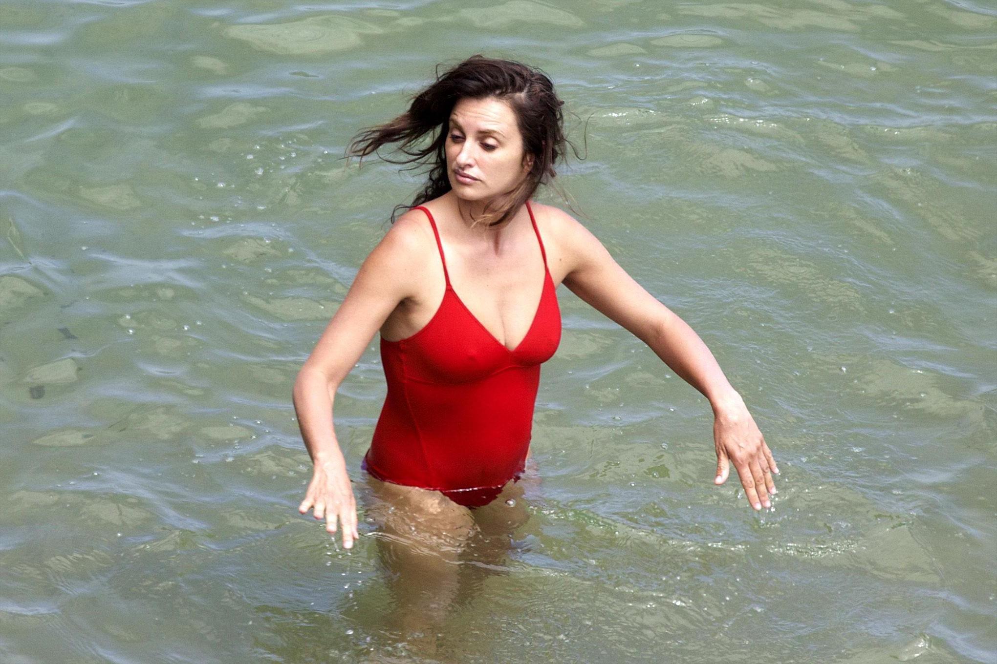 16P Penelope Cruz showing pokies on a beach wearing a sexy red swimsuit