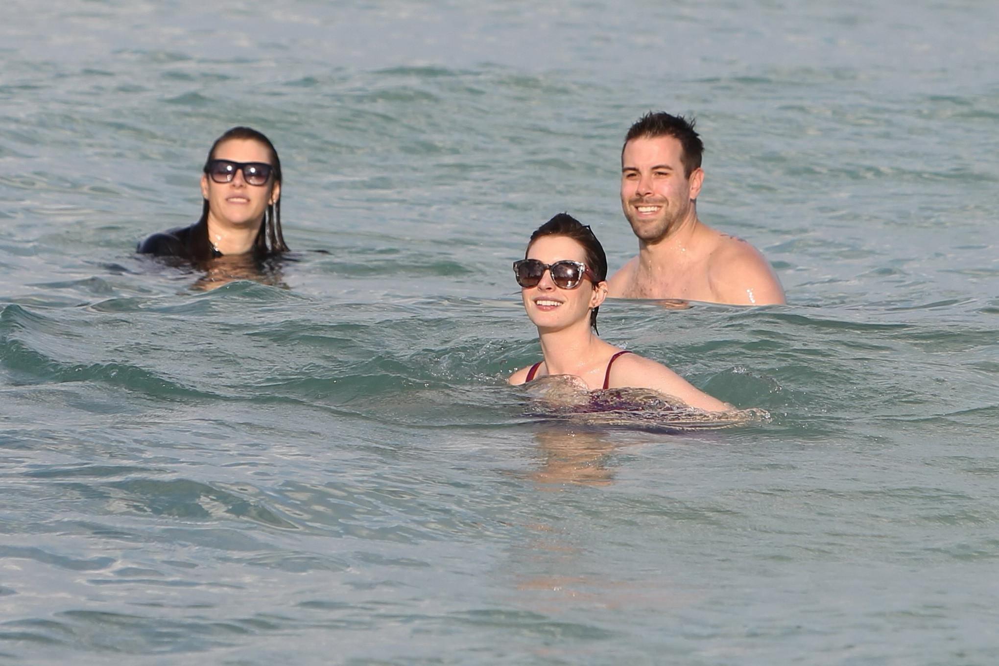16P Anne Hathaway wearing wet purple see-through swimsuit and shorts at the beach in