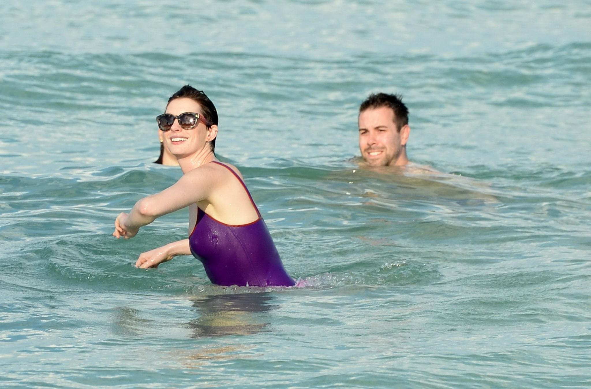 16P Anne Hathaway wearing wet purple see-through swimsuit and shorts at the beach in