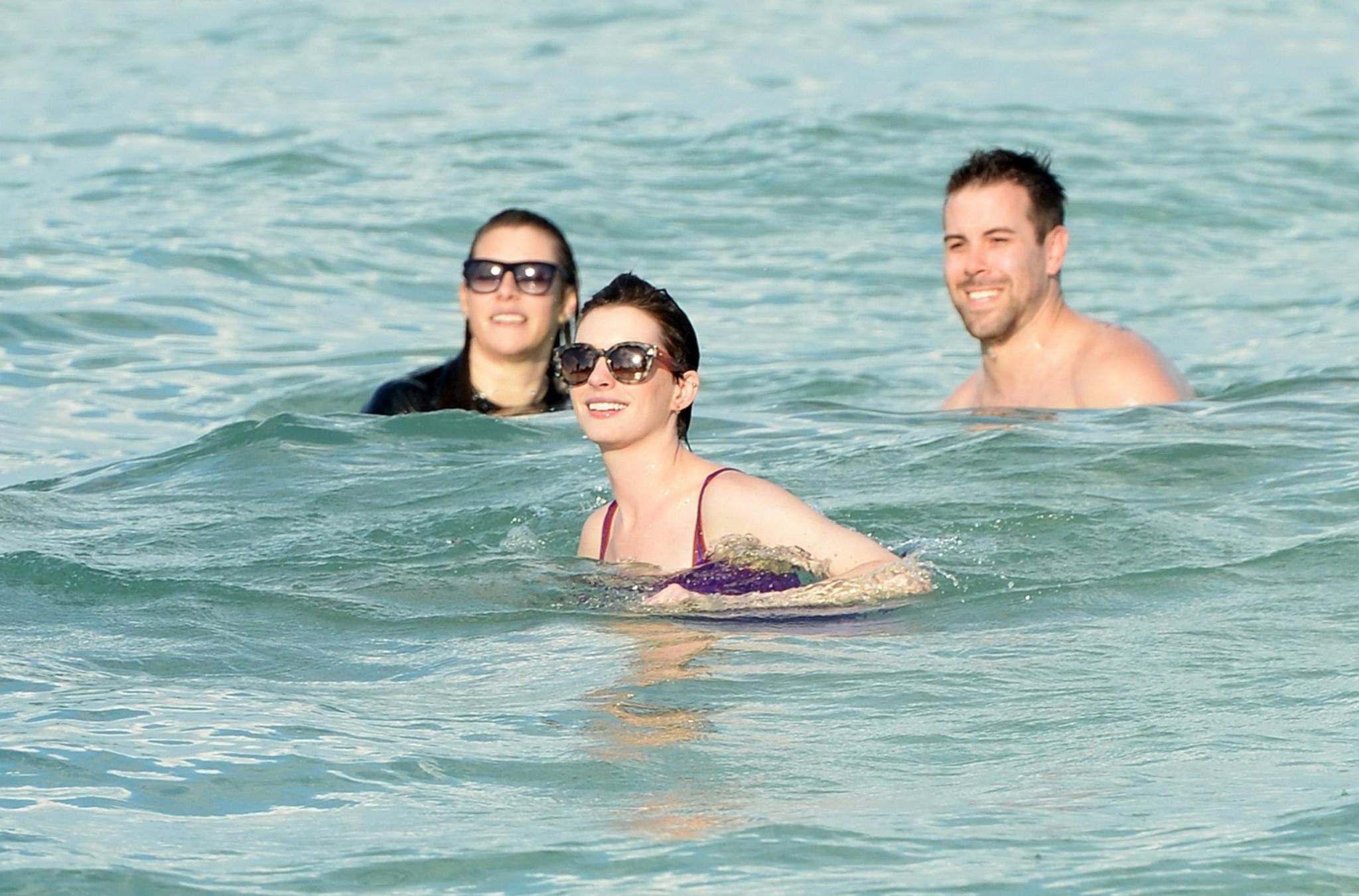 16P Anne Hathaway wearing wet purple see-through swimsuit and shorts at the beach in