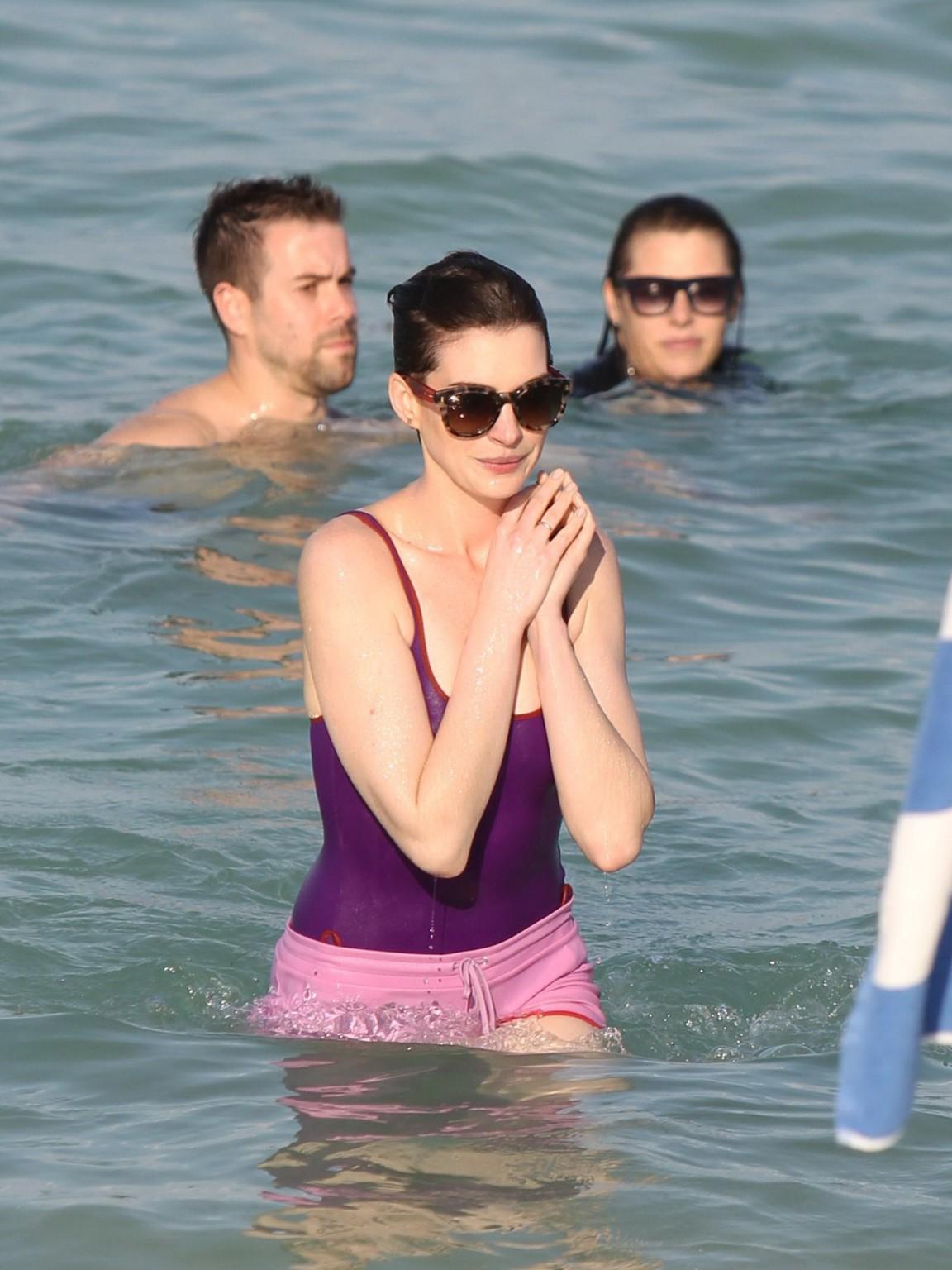 16P Anne Hathaway wearing wet purple see-through swimsuit and shorts at the beach in