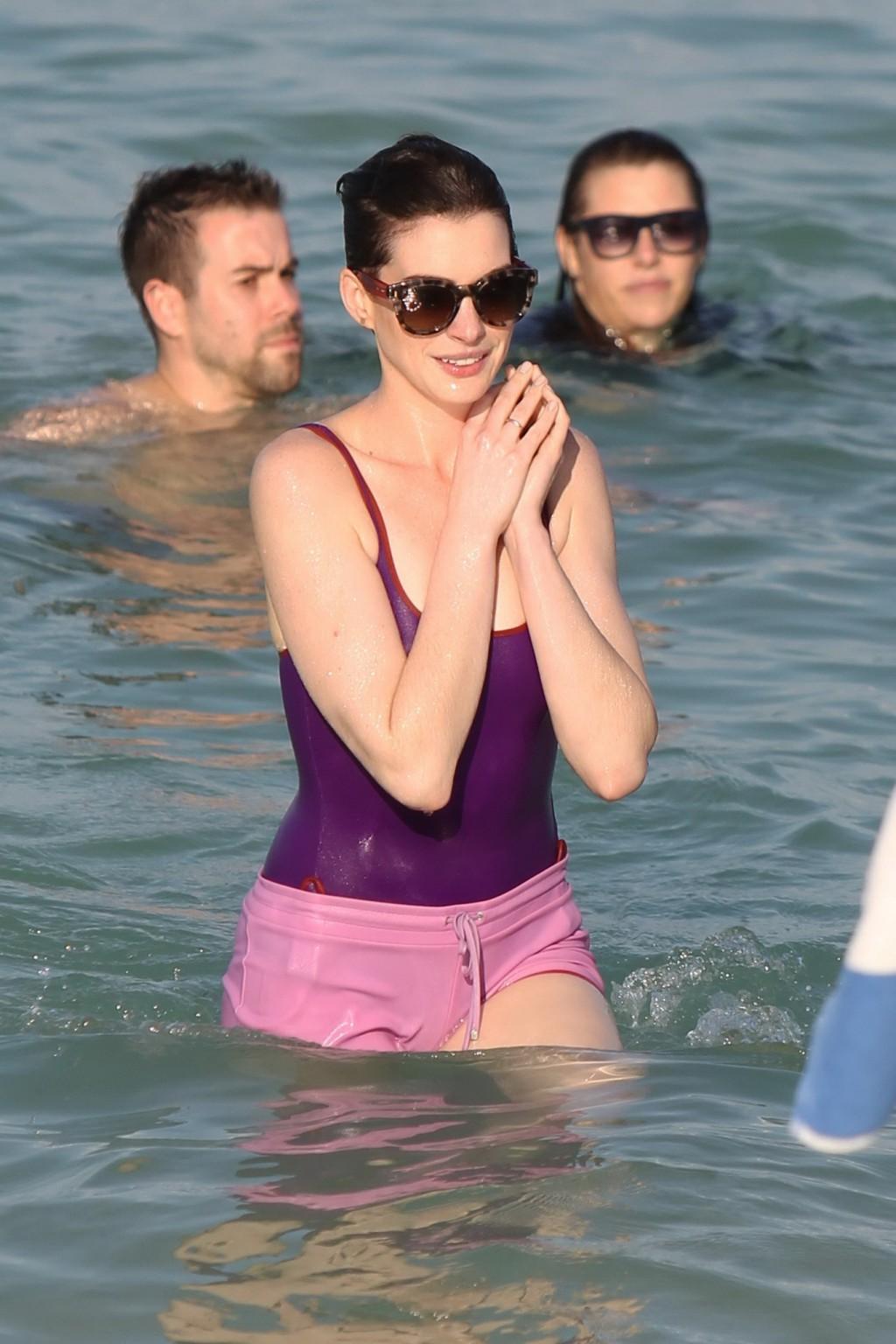 16P Anne Hathaway wearing wet purple see-through swimsuit and shorts at the beach in