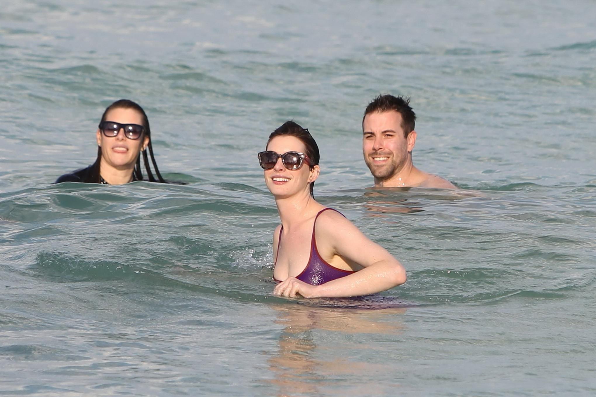 16P Anne Hathaway wearing wet purple see-through swimsuit and shorts at the beach in