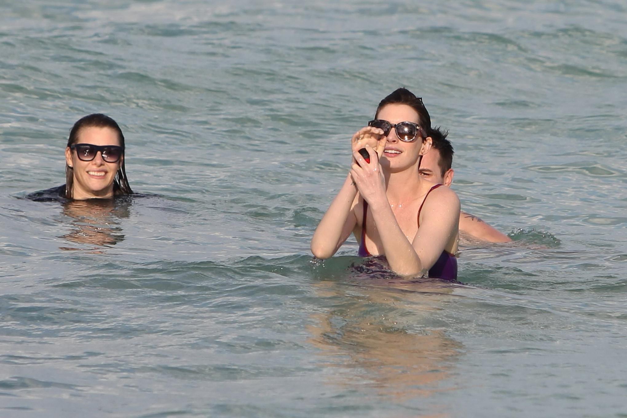 16P Anne Hathaway wearing wet purple see-through swimsuit and shorts at the beach in