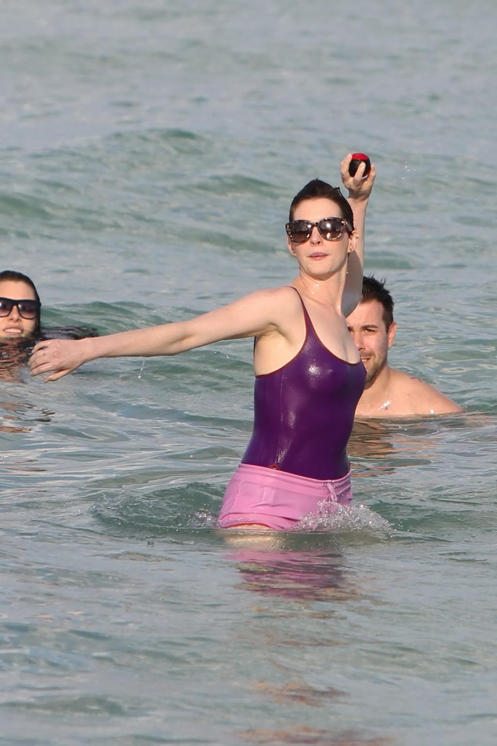 16P Anne Hathaway wearing wet purple see-through swimsuit and shorts at the beach in
