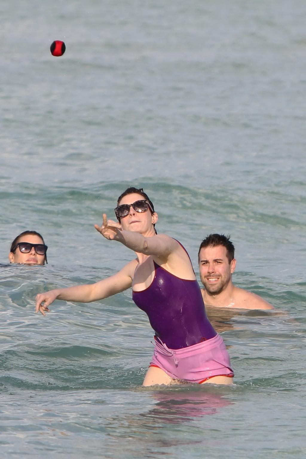 16P Anne Hathaway wearing wet purple see-through swimsuit and shorts at the beach in