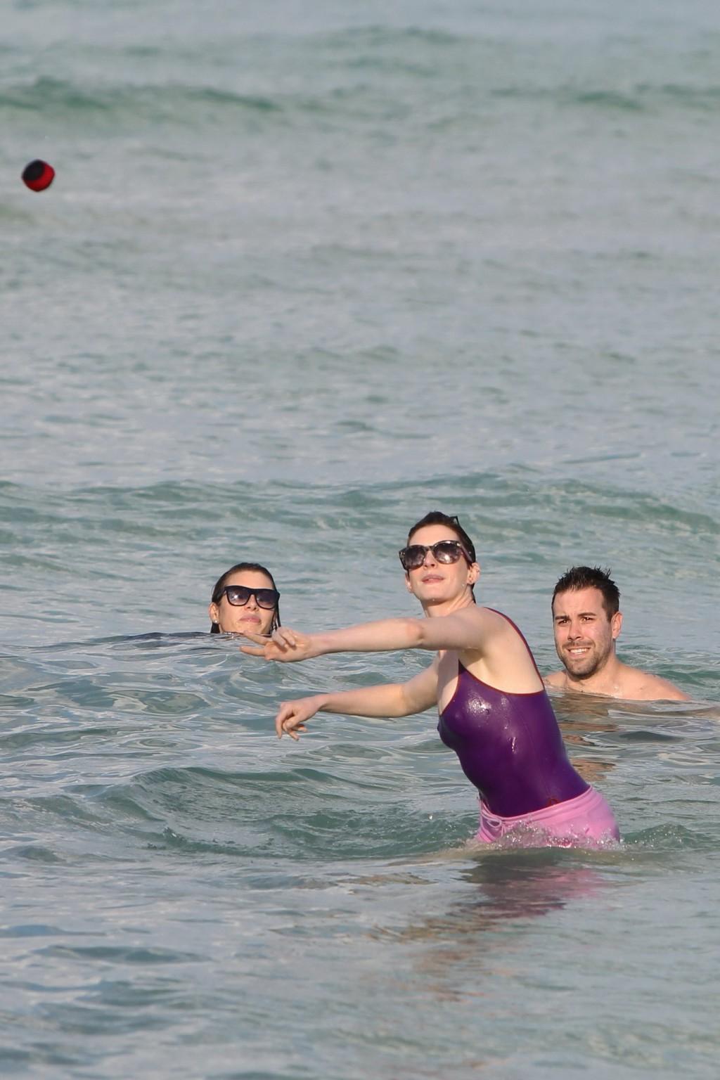 16P Anne Hathaway wearing wet purple see-through swimsuit and shorts at the beach in