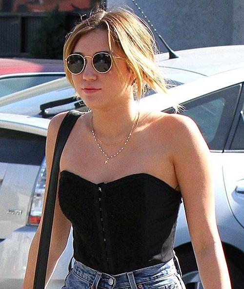 16P Miley Cyrus wearing a black corset and shorts on street