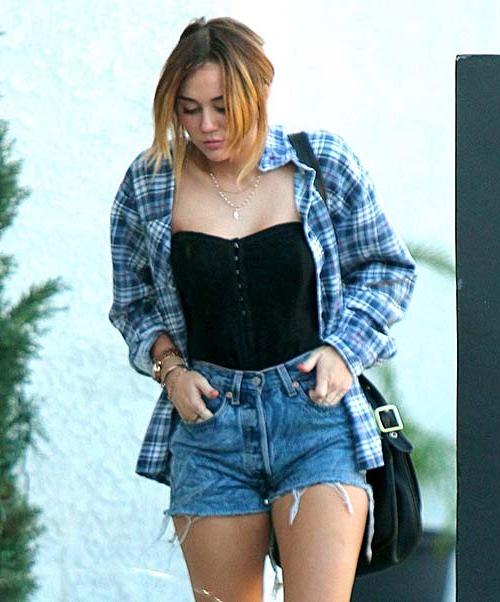 16P Miley Cyrus wearing a black corset and shorts on street