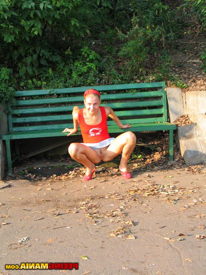 15P Yellow urine coming under blue and short jeans skirt by the green bench