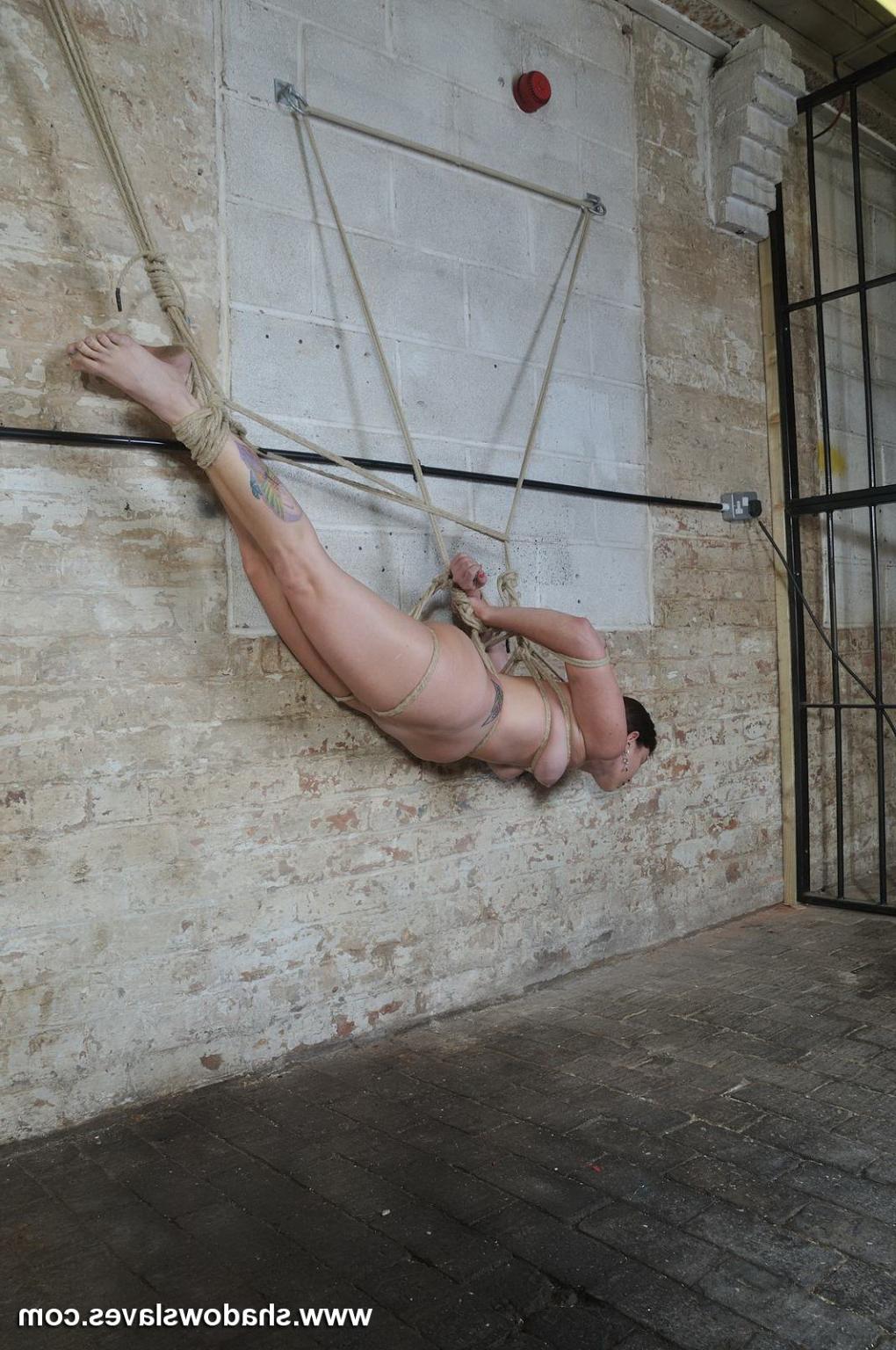 16P Amateur sub suspended in rope bondage against a wall