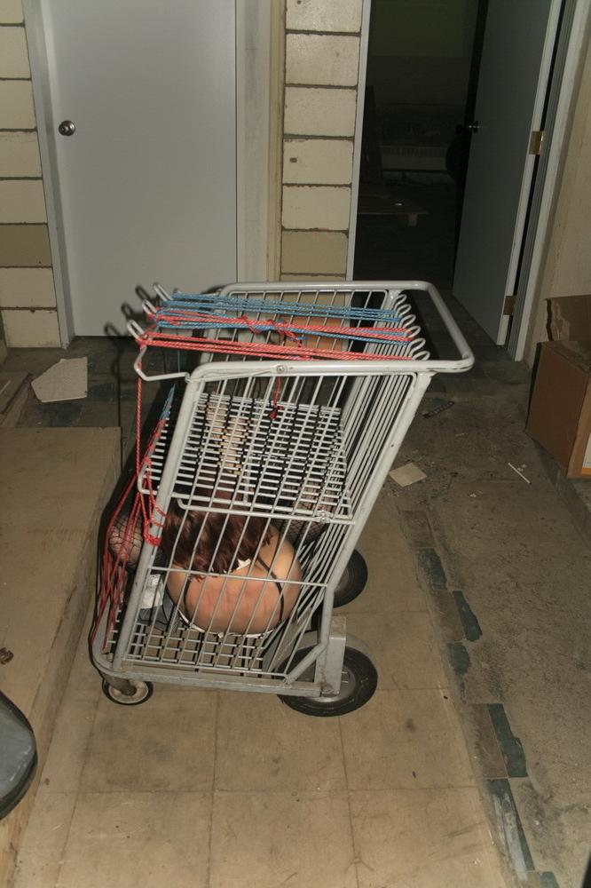 16P Marcy is tied tight into a tiny little cage on wheels.