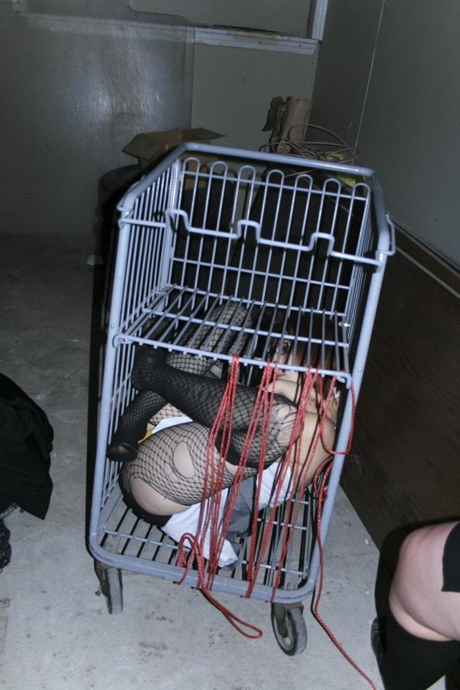 16P Marcy is tied tight into a tiny little cage on wheels.