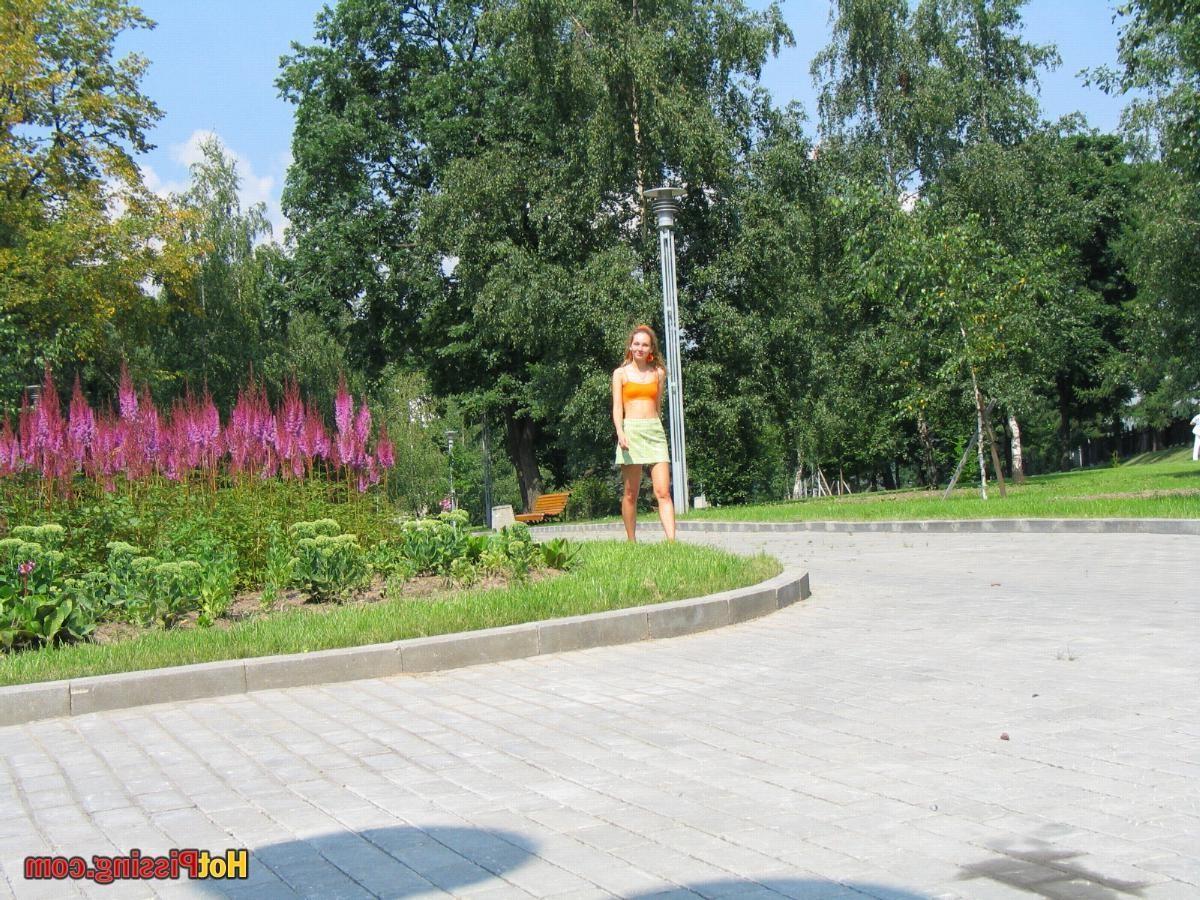 15P Babe in green and orange sits down on a border and does a piss coolly