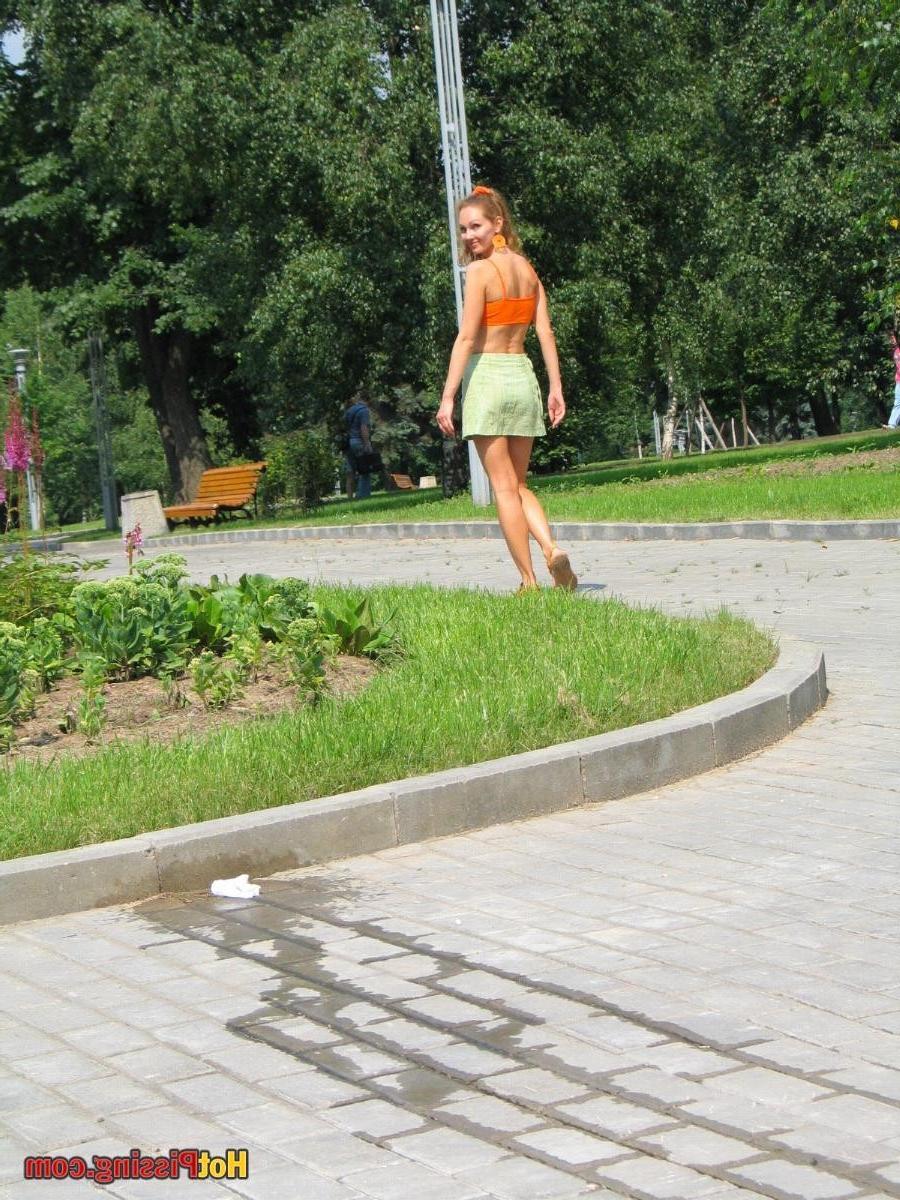 15P Babe in green and orange sits down on a border and does a piss coolly