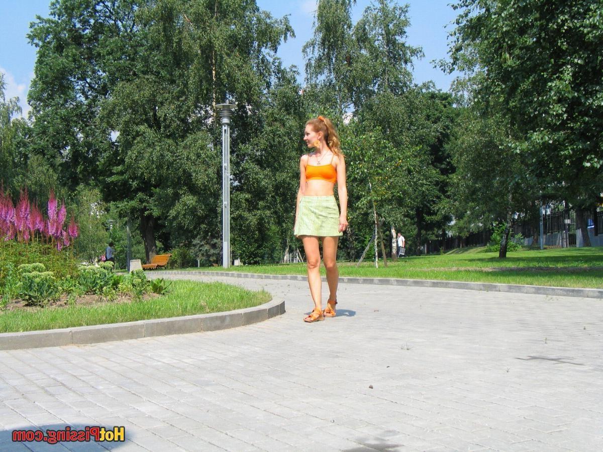 15P Babe in green and orange sits down on a border and does a piss coolly