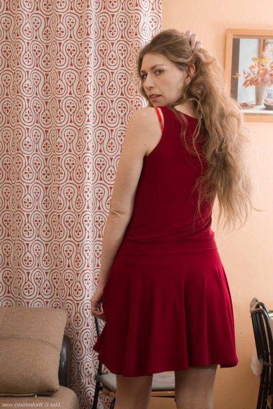 15P Elza strips naked on her brown couch looking sexy