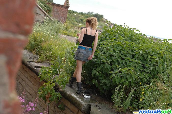 16P Cute young blondie makes water behind a lush shrub