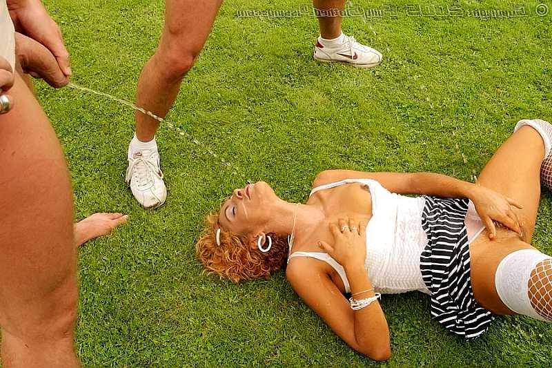20P Two guys pissing over a redhead on an outdoor soccer field