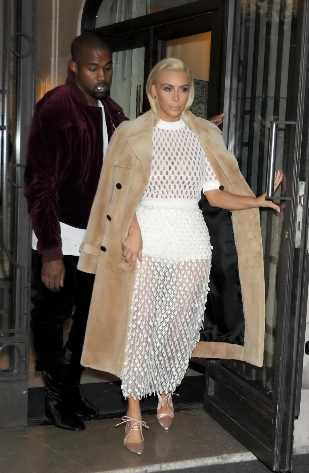 16P Kim Kardashian in a white mesh dress leaving her hotel in Paris
