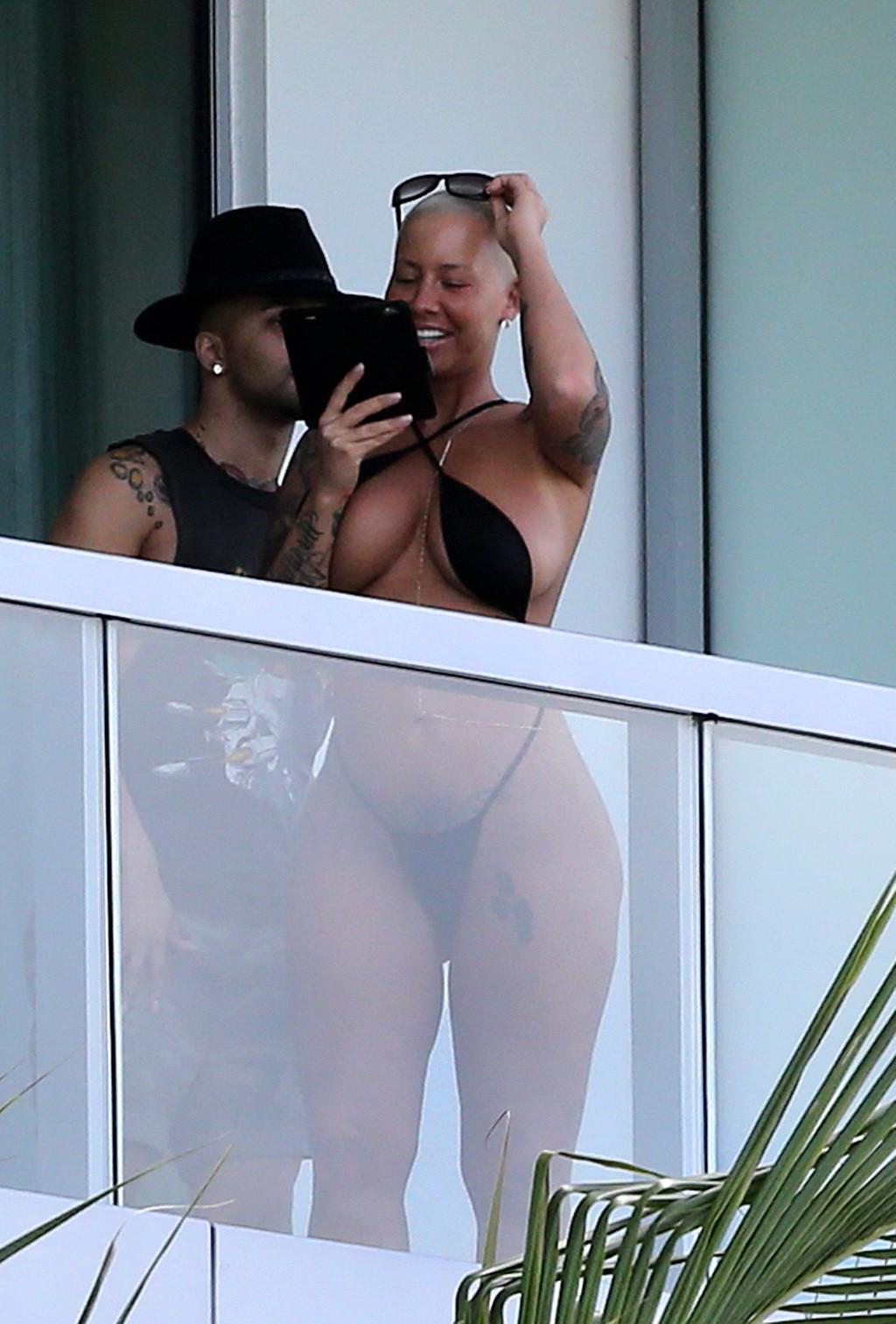 16P Amber Rose shows off her round ass wearing a tiny black monokini on a hotel balc