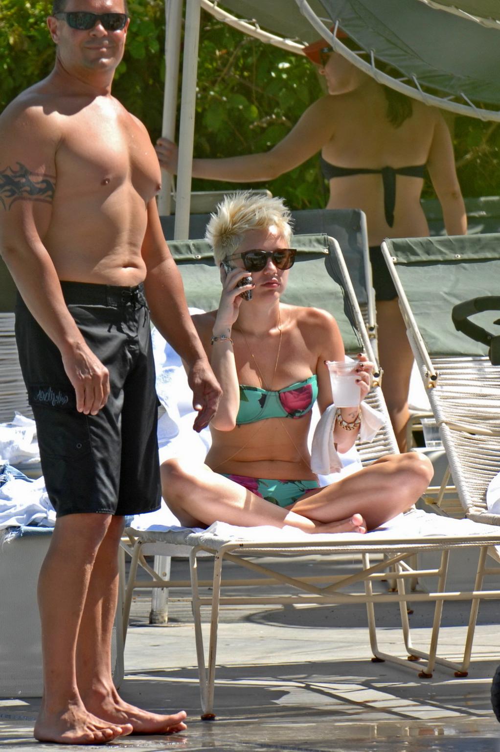 16P Miley Cyrus wearing floral tube bikini poolside at Palm Desert Hotel in Palm Spr
