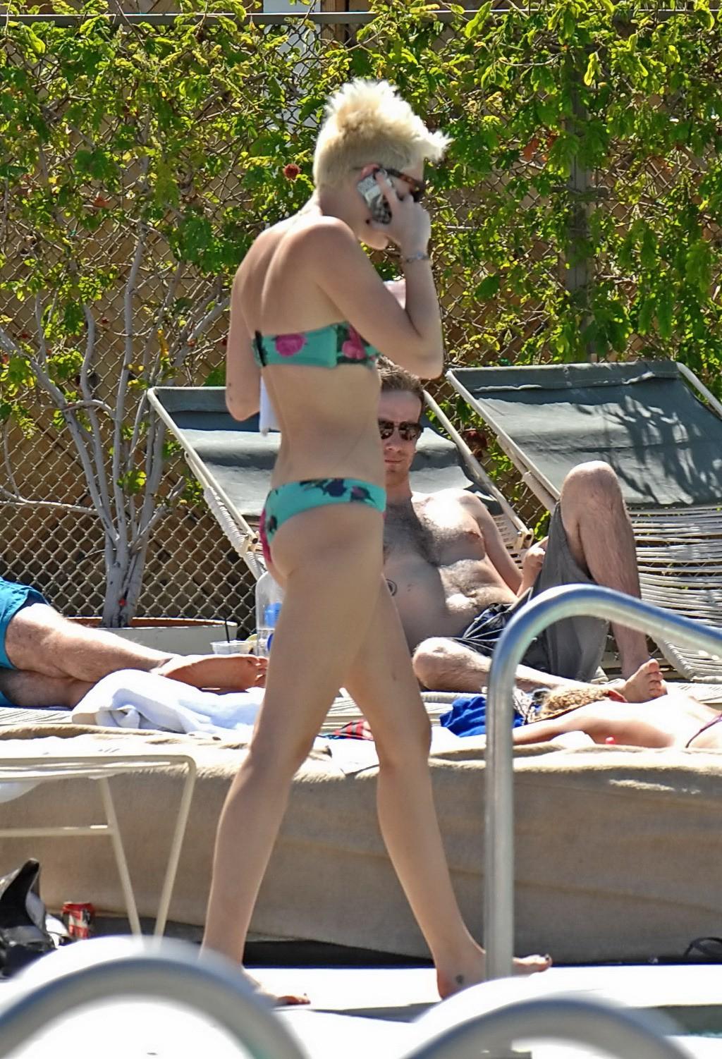 16P Miley Cyrus wearing floral tube bikini poolside at Palm Desert Hotel in Palm Spr