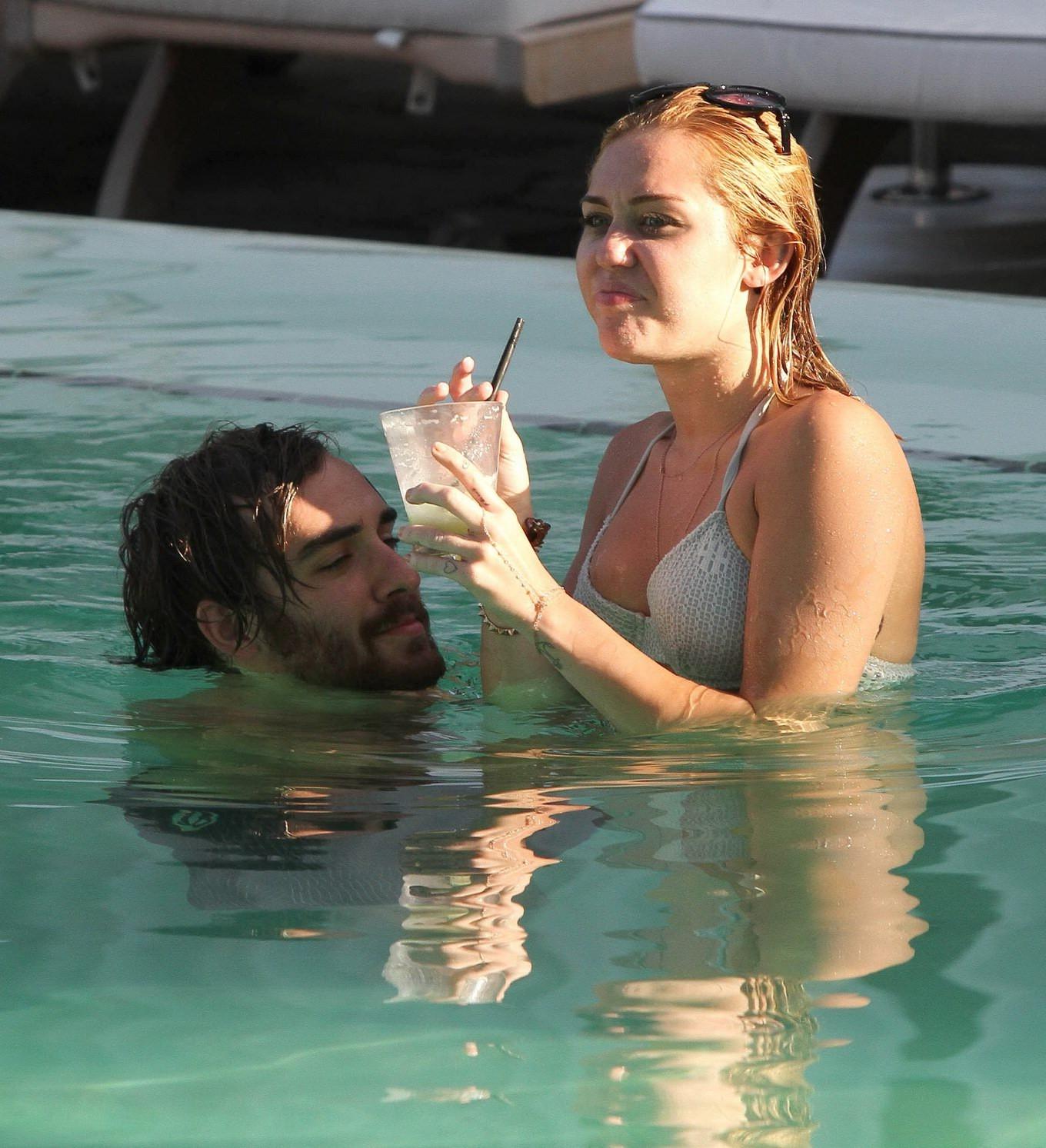 10P Miley Cyrus wearing white bikini at a hotel pool in Miami
