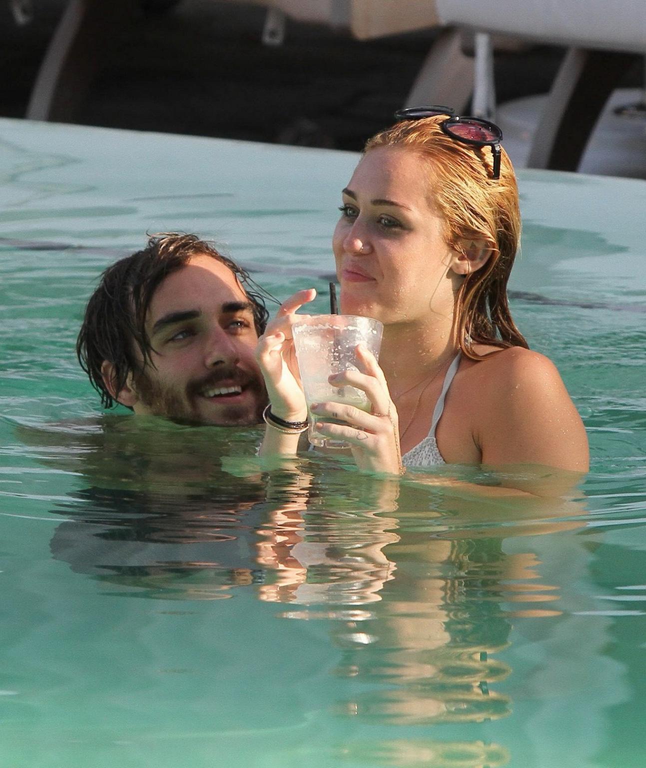 10P Miley Cyrus wearing white bikini at a hotel pool in Miami