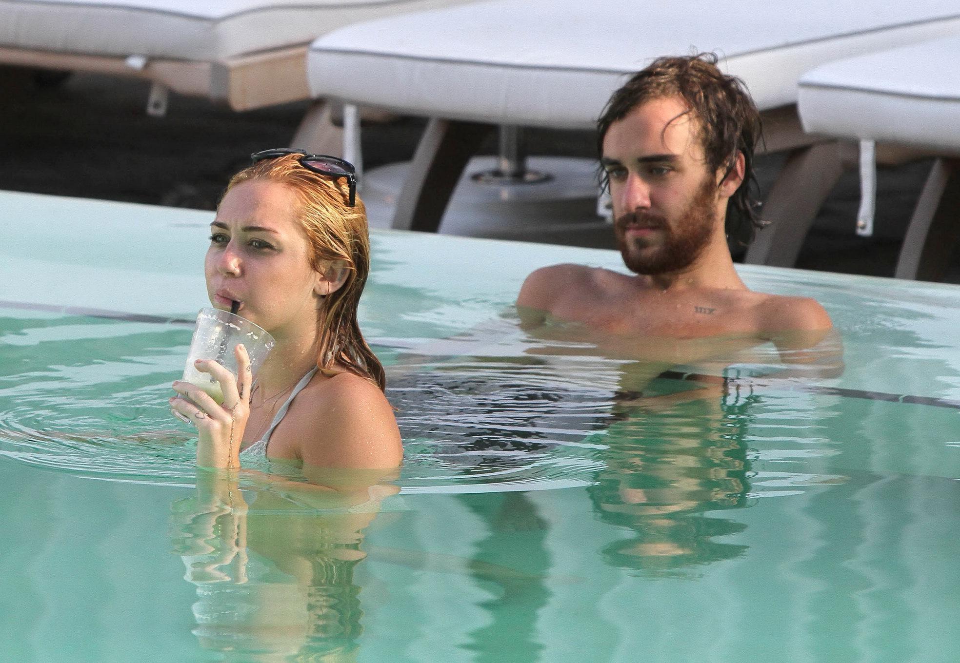 10P Miley Cyrus wearing white bikini at a hotel pool in Miami