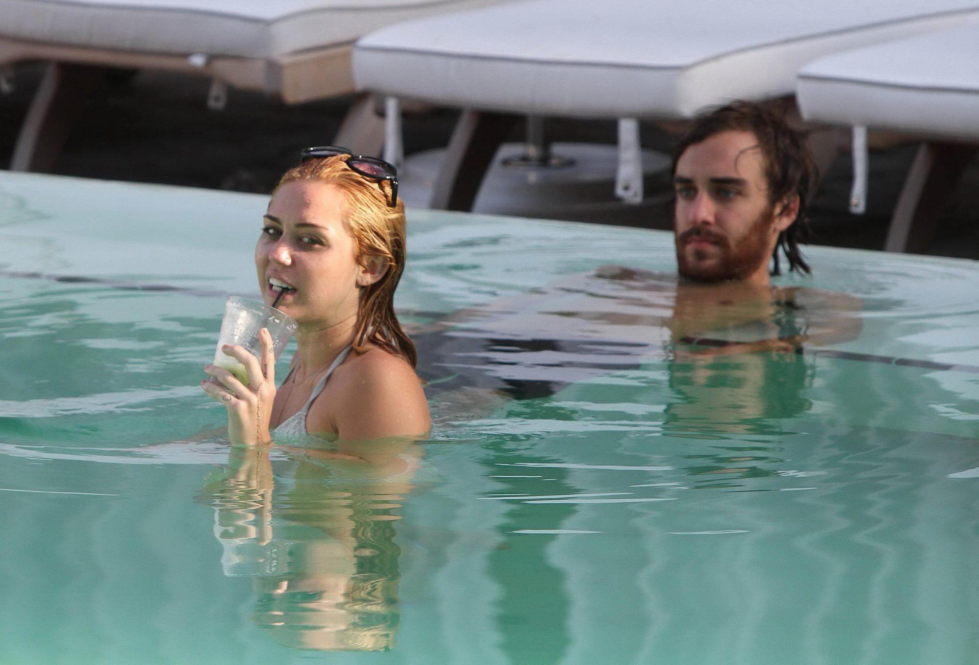 10P Miley Cyrus wearing white bikini at a hotel pool in Miami