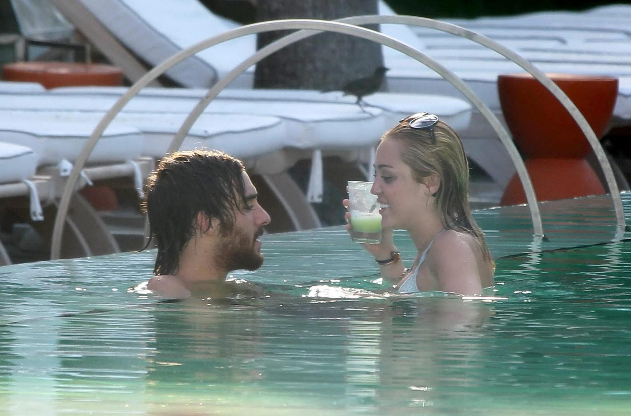 10P Miley Cyrus wearing white bikini at a hotel pool in Miami